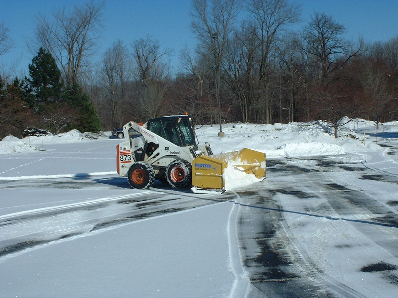 Skidsteer with Pusher Box Plowing Snow in Cleveland Parking Lot