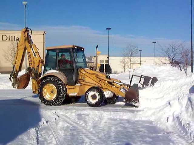 Backhoe Used for Plowing and Stacking Snow in Cleveland Parking Lot